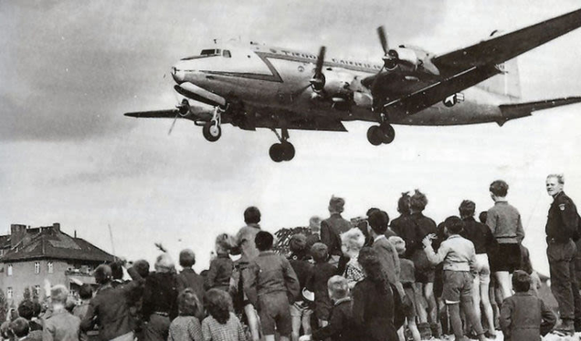 Residents of West Berlin watch as a US Air Force Douglas C-54 Skymaster lands at Tempelhof Airport. German children gathered under the landing area to catch candy dropped by Allied pilots in what became known as Operation Little Vittles. (US Air Force)